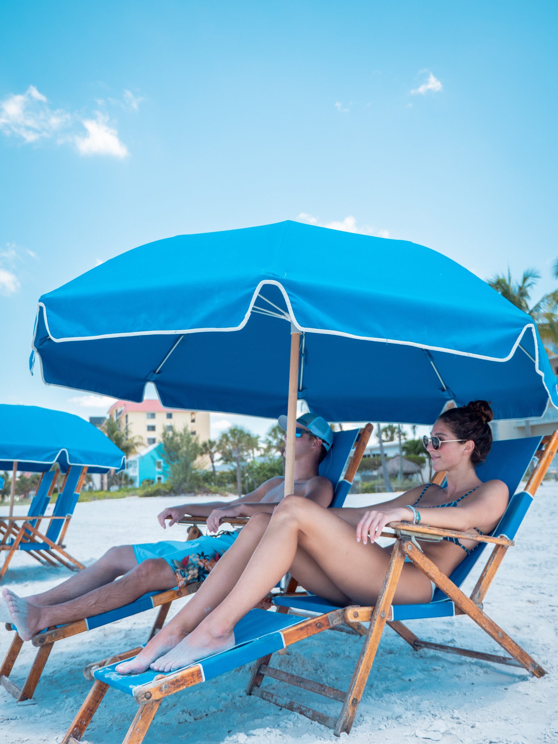 06 – Holiday (1 of 1)-41 a group of people sitting at a beach with a umbrella in the sand