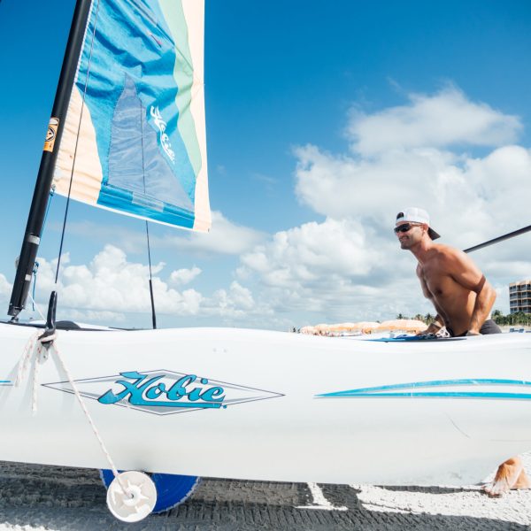 a person pushing a sailboat towards the water