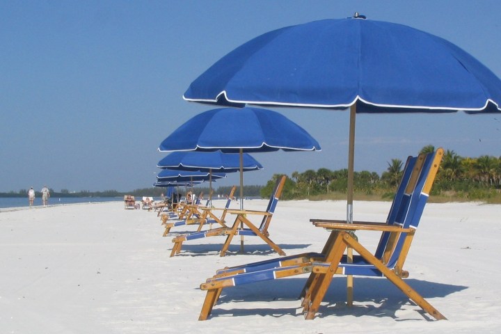 a couple of lawn chairs sitting on top of a sandy beach